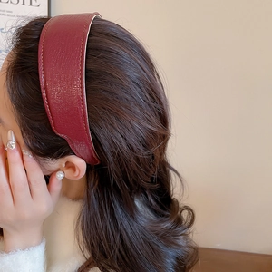 Side view of a wine red pleated leather headband worn for a high crown voluminous look