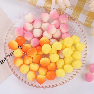 Mini TPR peach squeeze toys in pink, orange, and yellow displayed on a glass tray