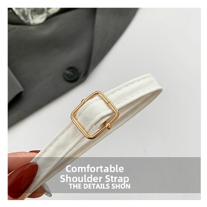 Detailed macro view of white adjustable PU leather shoulder strap with gold buckle