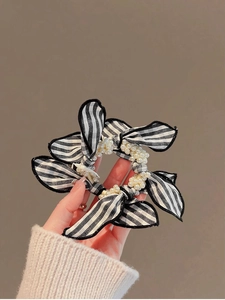 Detail of black and white striped bow hair scrunchie with elegant pearl decoration