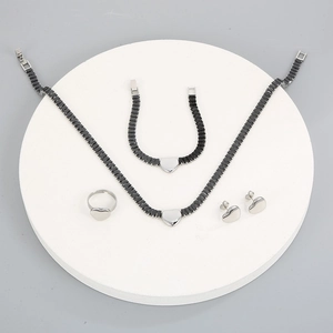 Détail macro d'un ensemble de bijoux en céramique noire et cœur argenté sur socle