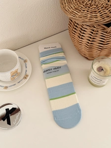 Close-up of striped cotton mid-calf socks with original paper card packaging on desk