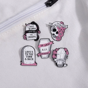 Pink gothic enamel pins set with skull flower and tombstone on white fabric