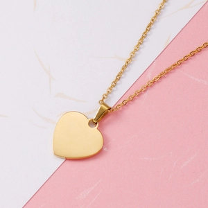 Polished gold heart pendant necklace for women on minimalist pink and white background