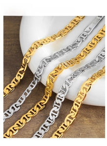 Detail of 18k gold and silver plated mariner link chains on a white ceramic display