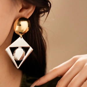 Minimalist geometric drop earrings featuring a gold sphere stud and silver hollow frame