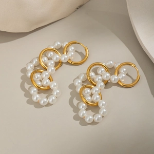 Detail of elegant gold hoop earrings with white pearl clusters and polished finish