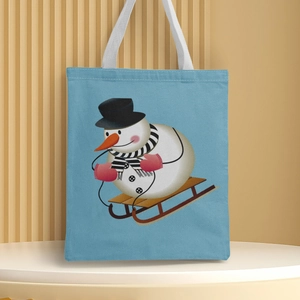 Detailed close-up of a blue Christmas canvas tote bag featuring a snowman on a sled print