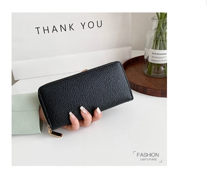 Detail of black pebbled leather long wallet for women with golden zipper hardware