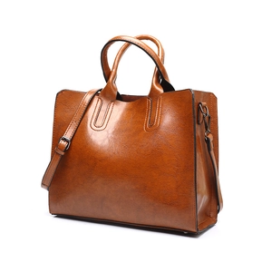 Detailed shot of brown PU leather tote bag with dark metal hardware and adjustable strap