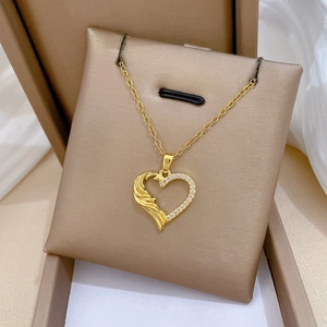Close-up of golden titanium heart necklace with wing texture and sparkling crystals