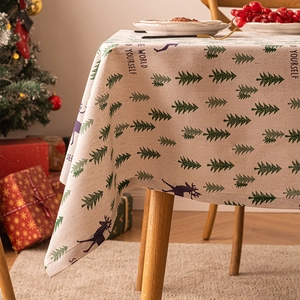 Christmas tablecloth with reindeer and pine trees on a wooden table setup