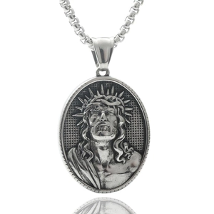 Macro shot of silver oval stainless steel pendant featuring vintage Jesus relief carving