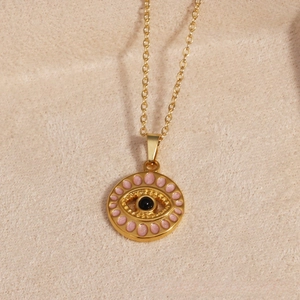 Detailed close-up of golden evil eye pendant necklace with pink enamel dots on o-chain