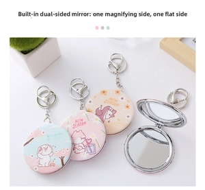 Detail of portable mini folding mirror keychain showing standard and magnifying lenses