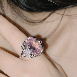 Macro shot of silver ring with large pink oval gemstone and crystal flower details