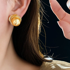 Macro view of gold flower earrings with large pearl and shimmering zircon stones