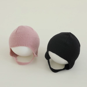 Dettaglio di berretti in maglia per neonati rosa e neri con paraorecchie e lacci caldi