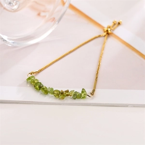 Detail of adjustable gold-tone chain bracelet with natural green gravel gemstones