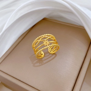 Détail d'une bague dorée réglable à trois couches avec motif soleil sur fond de soie
