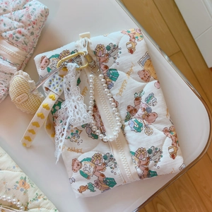 Macro detail of quilted cotton bag with bear patterns, lace bow and pearl chain handle