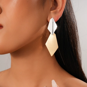 Close-up of geometric diamond earrings with silver glossy and gold brushed metal texture