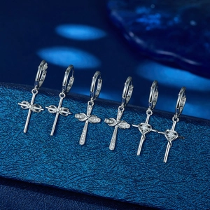 Detailed macro of six 925 sterling silver hoop earrings with dangling cross pendants