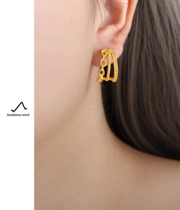 Close-up of triple-layered C-shaped gold hoop earrings made of textured stainless steel