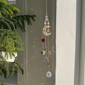 Detail of moon sun catcher crystal with colorful heart prisms and golden chains