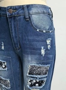 Detailansicht von Damen-Jeanshosen mit Totenkopf-Patches und Pailletten in Destroyed-Optik