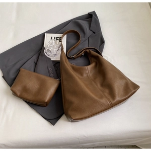 Detail of soft leather dark brown tote bag set with matching inner pouch on stylish background