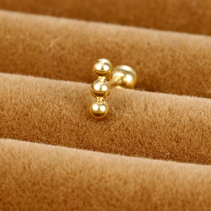 Macro shot of three golden stainless steel beads on a ball-back cartilage stud earring