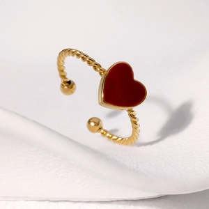 Close-up of gold twist ring featuring a red enamel heart and adjustable open band