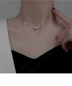Detail of silver-tone titanium steel bean pendant necklace on a delicate chain