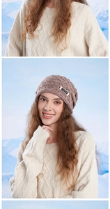 Detail of a brown knit beanie featuring a white -JOYORD- label against a snowy backdrop