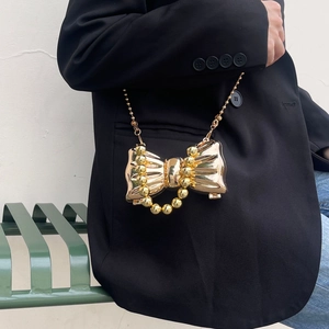 Borsa a tracolla dorata metallica a forma di fiocco con catena su modella