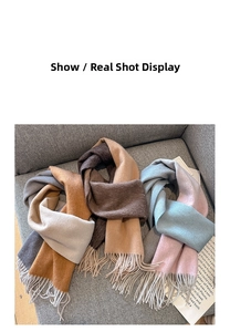 Detail of cashmere-like scarves with fringe edges in gradient earth tones on a grey sofa