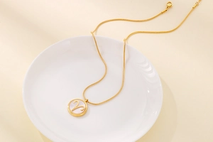 Detail of Aries zodiac pendant with white shell inlay on a golden snake chain necklace