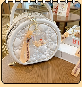 Detail of Capybara acrylic keychain with orange strap on a white quilted circle bag