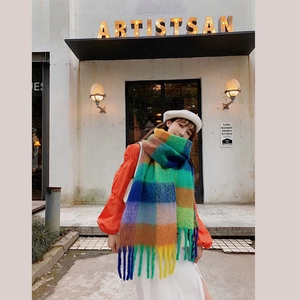 Detailed close-up of rainbow plaid tassel scarf worn by model near a boutique shop