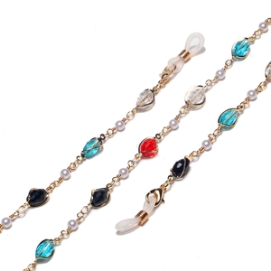 Gold glasses chain with colorful crystal beads and white pearls on white background