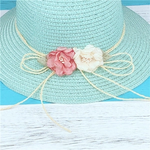 Vue détaillée d'un chapeau de soleil en paille vert menthe orné de fleurs en tissu