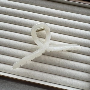 Close-up of cream marble hair claw clip with golden spring on velvet jewelry tray