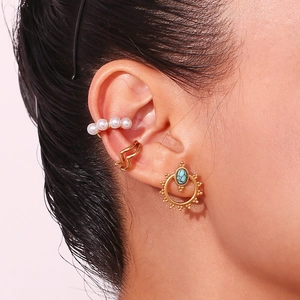 Close-up of bohemian turquoise stud earring and golden ear cuffs on a female ear