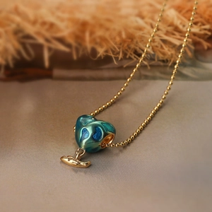 Gold heart-shaped enamel necklace with blue-green swirl pattern and whale charm pendant