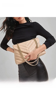 Detail of beige quilted leather handbag featuring V-stitch and gold chain strap on model