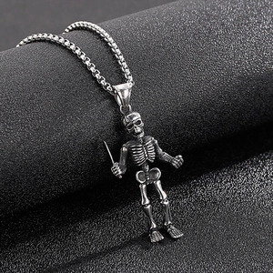 Detailed view of vintage skeleton pendant holding sword on stainless steel box chain
