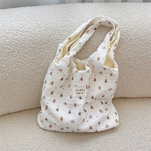 Detail of white quilted fabric with brown bear prints and colorful embroidered patch