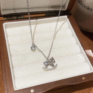 Gros plan d'un pendentif cheval à bascule argenté avec strass sur un coffret en bois