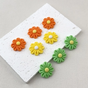 Flat lay of colorful resin flower charms with knit texture for DIY phone case crafts